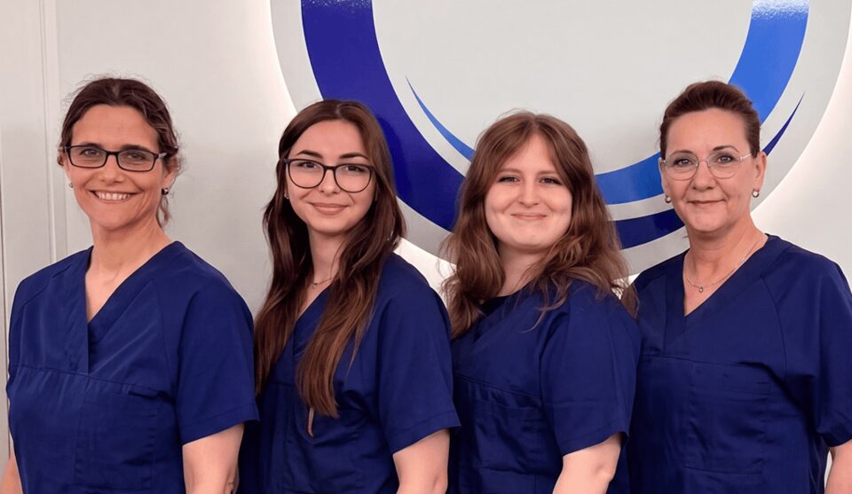 Vier Mitarbeiterinnen der Praxis für Oralchirurgie Puchheim in blauer Praxiskleidung